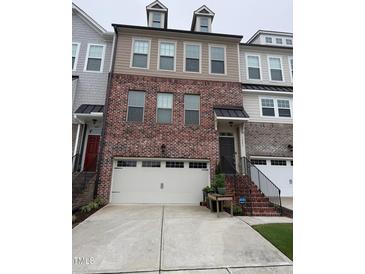 Charming townhome featuring a brick facade, a two-car garage, and a welcoming entrance with black metal handrails at 1005 Lathrop Ln, Apex, NC 27523
