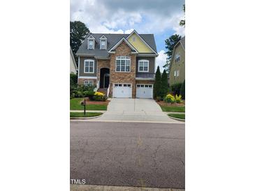 Charming two-story home featuring a stone facade, a two-car garage, and a beautifully landscaped front yard at 1016 Dotson Way, Apex, NC 27523