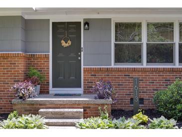 Charming home entrance featuring a gray door, brick accents, and well-manicured landscaping at 1613 Euclid Rd, Durham, NC 27713