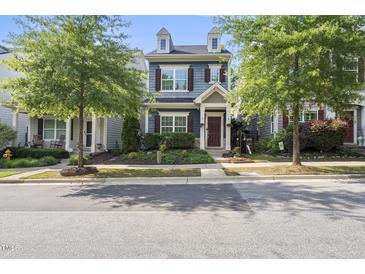 Charming two-story home with blue siding, brown shutters and a nicely landscaped front yard and trees at 1625 Main Divide Dr, Wake Forest, NC 27587