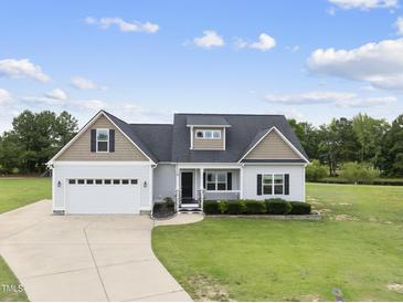Inviting exterior showcases well-manicured lawn, attached two-car garage, and charming front porch at 241 Fox Run, Benson, NC 27504