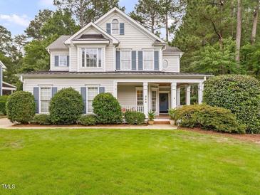 Charming two-story home featuring a lush green lawn, covered front porch, and classic architectural details at 244 Elmcrest Dr, Holly Springs, NC 27540