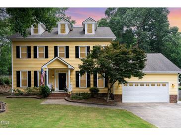 Charming yellow two-story home with black shutters and manicured lawn and white garage door at 1001 Kingsway Dr, Apex, NC 27502