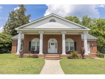 Charming brick home featuring a columned front porch and a well-manicured lawn at 219 E Nash St, Spring Hope, NC 27882
