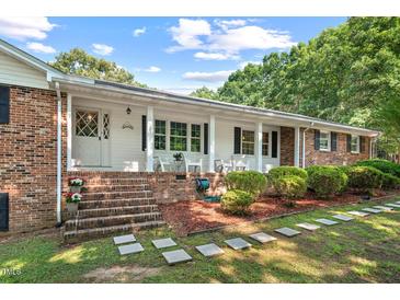 Charming brick home with a covered front porch, landscaped yard, and stepping stones pathway at 5414 Ventoria Rd, Durham, NC 27712