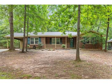 Charming brick home with a cozy front porch and well-maintained landscaping surrounded by mature trees at 809 Valerie Dr, Raleigh, NC 27606