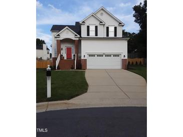 Charming two-story home boasts a well-manicured lawn, brick accents and a bright red front door at 8600 Colville Ct, Raleigh, NC 27617