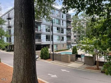 Modern condo building featuring a swimming pool, balcony, and lush trees around at 1300 St Marys St # 402, Raleigh, NC 27605