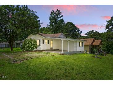 Charming one-story home featuring a covered porch, well-maintained lawn, and lovely landscaped surroundings at 16 S Church, Coats, NC 27521
