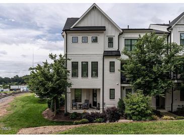 Charming three-story townhouse boasts white brick, black trim and inviting front porch with lush landscaping at 1610 Draper View Loop # 101, Raleigh, NC 27608