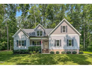Charming home featuring tidy landscaping, a welcoming front porch, and a classic American flag at 167 Sequoia Dr, Timberlake, NC 27583