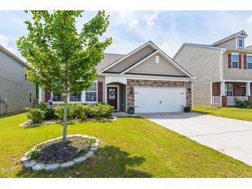 Charming home with a stone accent facade, well-manicured lawn, and a two-car garage at 202 E Painted Way, Clayton, NC 27527
