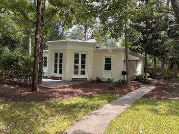 Charming home featuring a light yellow brick exterior, elegant white trim, and lush landscaping at 2428 Perkins Rd, Durham, NC 27705