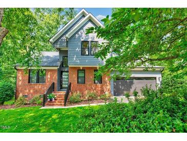 Charming two-story home boasts a brick facade, gray siding, manicured lawn, and lush greenery for added curb appeal at 306 Roebling Ln, Cary, NC 27513