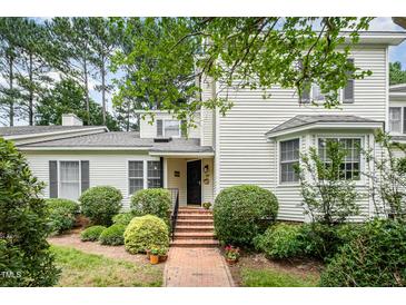 Charming home with a brick walkway leading to the entrance, complemented by lush landscaping and mature trees at 384 Lyndfield Cl W, Pittsboro, NC 27312