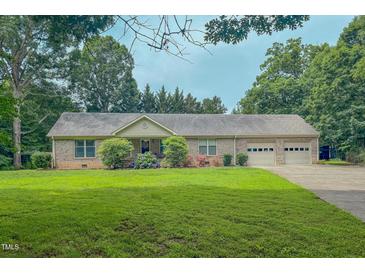 Charming brick home features an attached two-car garage and well-maintained lawn at 6305 Holly Ridge Rd, Rougemont, NC 27572