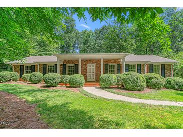 Charming brick home featuring a well-manicured lawn, lush landscaping, and a welcoming front entrance at 712 Orange High School Rd, Hillsborough, NC 27278