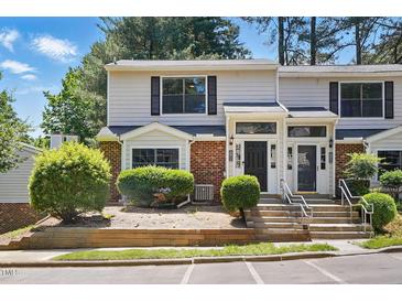 Inviting townhouse with brick facade, manicured greenery, and steps leading to a covered entrance at 7708 Falcon Rest Cir, Raleigh, NC 27615