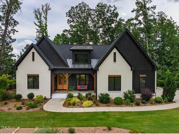 Charming, modern home with a combination of white-painted brick and black accents and lush front yard landscaping at 153 W Beech Slope Ct, Chapel Hill, NC 27517