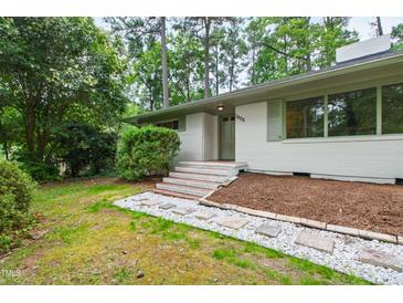 Charming single-story home with white brick, green trim, and a well-manicured front yard landscape at 1606 Sycamore St, Durham, NC 27707