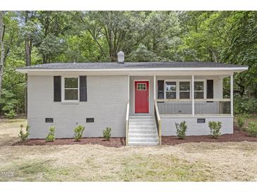 Charming brick home with a vibrant red front door and covered porch, surrounded by lush greenery at 2702 Red Valley Dr, Rougemont, NC 27572