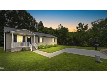 Charming home exterior featuring a well-maintained lawn, paved driveway and inviting front porch at 427 Elm Ct, Burlington, NC 27217