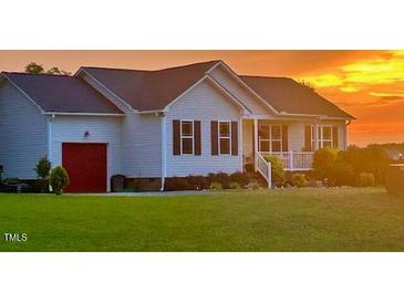 Charming single-story home with a well-manicured lawn and red garage door, bathed in a beautiful sunset at 56 Sugarhill Dr, Zebulon, NC 27597