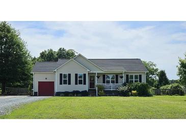 Charming one-story home features a welcoming front porch and well-manicured lawn, red garage door, and black shutters at 56 Sugarhill Dr, Zebulon, NC 27597