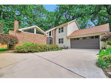 Charming two-story home featuring a brick accent wall, a large driveway, and an attached two-car garage at 6701 Winding Trail Trl, Raleigh, NC 27612