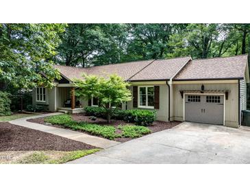 Charming home featuring a well-manicured lawn, mature trees, and a convenient attached garage at 7016 Valley Dr, Raleigh, NC 27612