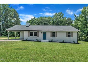 Charming single-story home featuring a painted brick facade, well-manicured lawn and a covered side entry at 802 Creech Church Rd, Kenly, NC 27542