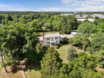 Picturesque two-story home featuring a metal roof, a charming balcony, and mature landscaping, nestled among lush trees at 301 W Thorndale Dr, Oxford, NC 27565