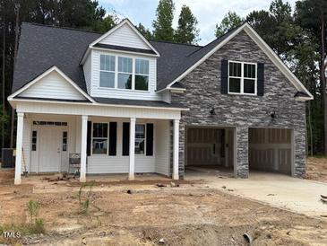 Charming new two-story home boasts stone accents, black shutters, a two-car garage, and a covered front porch at 400 Abingdon Farms Dr, Selma, NC 27576