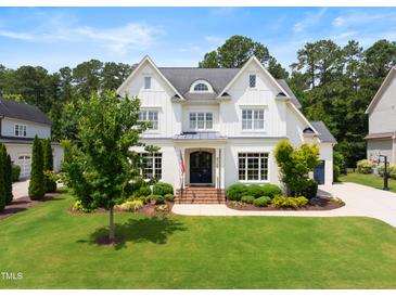Charming two-story white home boasting a manicured lawn, lush landscaping, and classic architectural details at 4729 Adler Pass, Raleigh, NC 27612