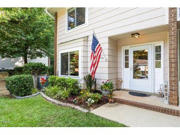 Inviting home entrance with an American flag and a well-manicured garden and decorative plants at 6021 Dixon Dr, Raleigh, NC 27609