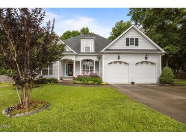 Charming two-story home with a well-manicured lawn, flowering plants, and a two car garage at 8116 Mosby Way, Willow Springs, NC 27592