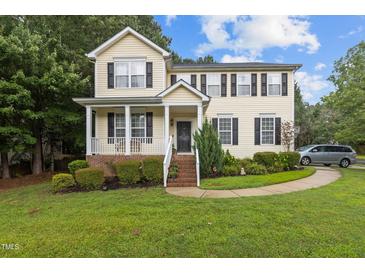 Charming two-story home with a well-manicured lawn and a welcoming front porch and black shutters at 136 Garden Retreat Dr, Garner, NC 27529