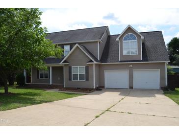 Charming two-story home with a two car garage and manicured lawn and a mature tree at 136 Wedgewood Ct, Sanford, NC 27332