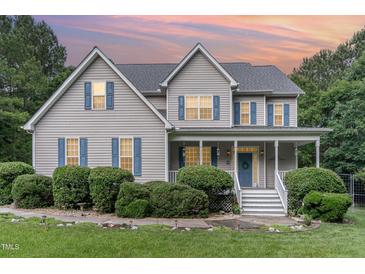 Charming two-story home with a cozy front porch, blue shutters, and meticulously landscaped front yard at 457 Poplar Forest Ln, Pittsboro, NC 27312