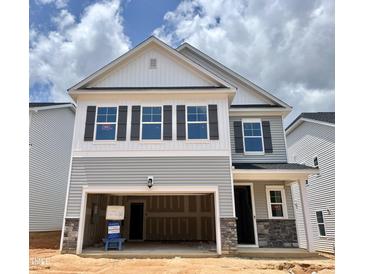 Charming two-story home showcasing a covered entryway, two-car garage, and beautiful architectural details at 709 Emerald Bay Cir # 833, Raleigh, NC 27610