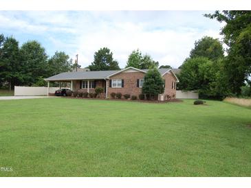 Charming brick ranch-style home with mature trees, lush green lawn, and convenient carport at 1418 Sherron Rd, Durham, NC 27703