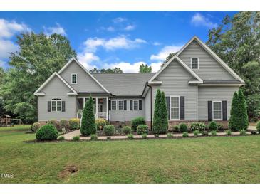 Charming two-story home featuring manicured landscaping, gray siding, black shutters, and a welcoming front porch at 152 Abundant Ave, Angier, NC 27501