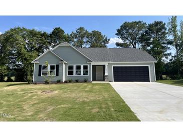 Charming single-story home featuring a well-manicured lawn and a convenient two-car garage at 168 Oakfield Trace Dr, Four Oaks, NC 27524