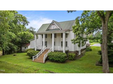 Stately two-story home with white siding, a metal roof, and a welcoming front porch with grand columns at 4053 Friendship Patterson Mill Road, Burlington, NC 27215