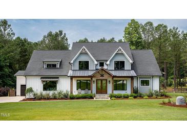 Charming two-story home with a combination of white siding, grey shingles and professionally landscaped front yard at 46 Lakes Edge Ln, Pittsboro, NC 27312