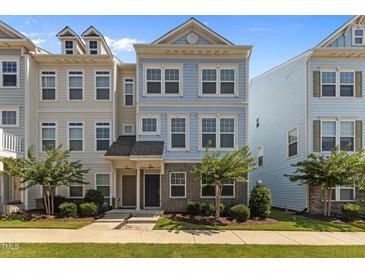 Charming two-story townhome featuring a well-manicured lawn and stylish architectural details at 319 Great Northern Station Sta, Apex, NC 27502