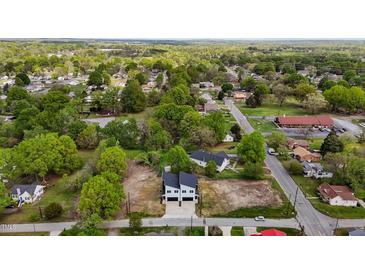 An aerial view of a neighborhood shows a new, two-story home surrounded by lush trees and greenery at 834-836 Day Ave, Burlington, NC 27217