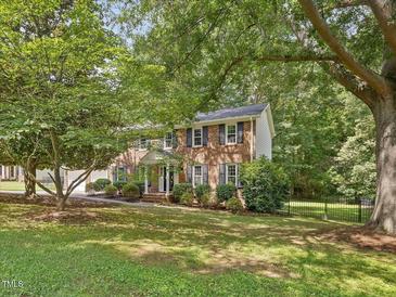 Charming brick home with lush landscaping and a welcoming front porch, perfect for enjoying the outdoors at 128 Castlewood Dr, Cary, NC 27511