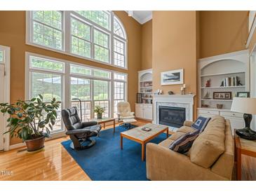 Bright living room boasts soaring ceilings, a fireplace with built-ins, and large windows that flood the space with natural light at 4613 Moores Creek Rd, Durham, NC 27705