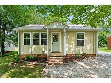 Charming single-story home featuring a quaint entrance, metal roof, and a well-maintained landscaped front yard at 502 S Eighth St, Mebane, NC 27302